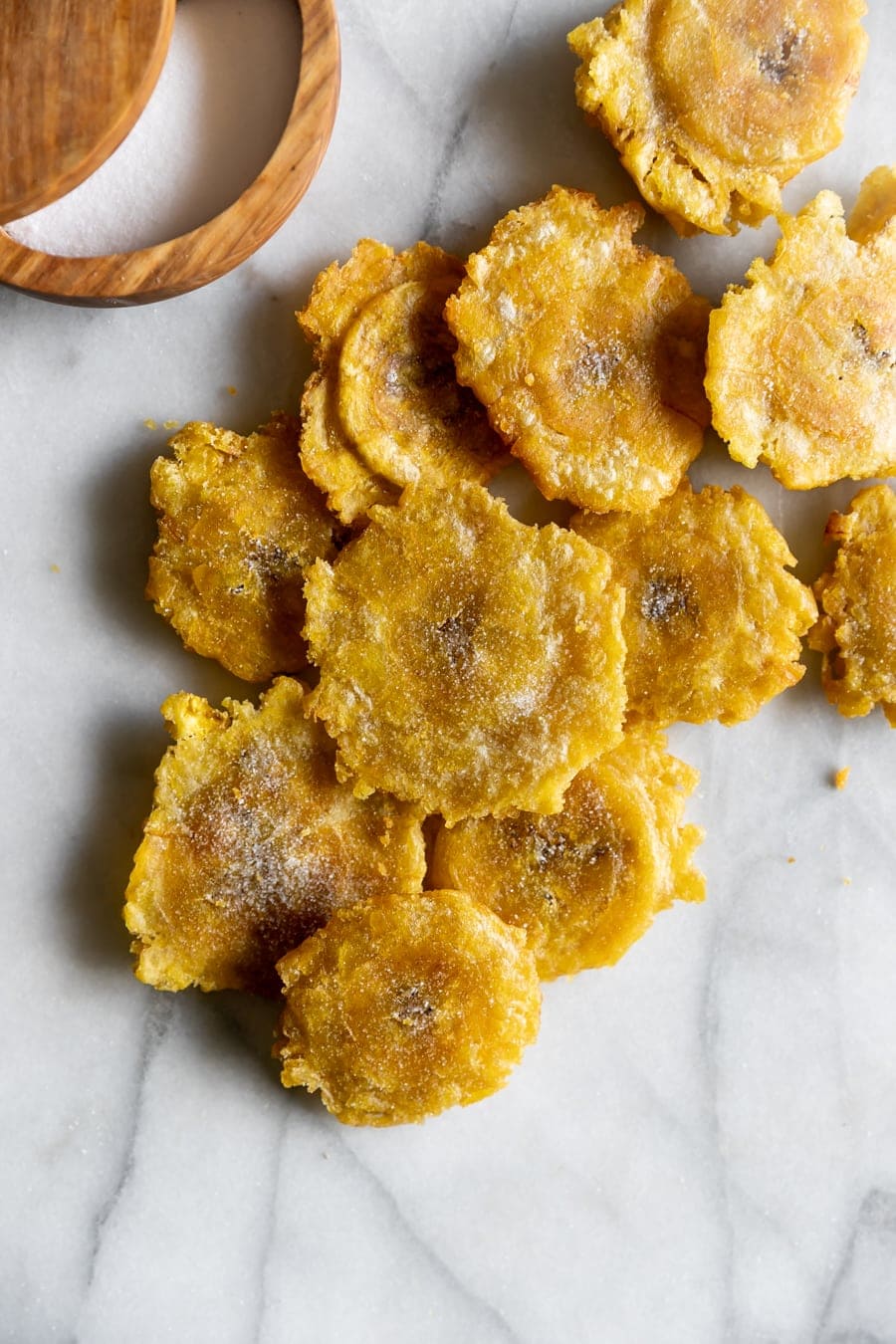 twice fried plantains tostones on a marble table with salt