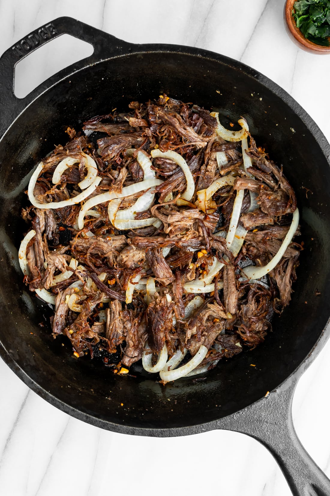 vaca frita with sautéed onions in a pan after being fried.