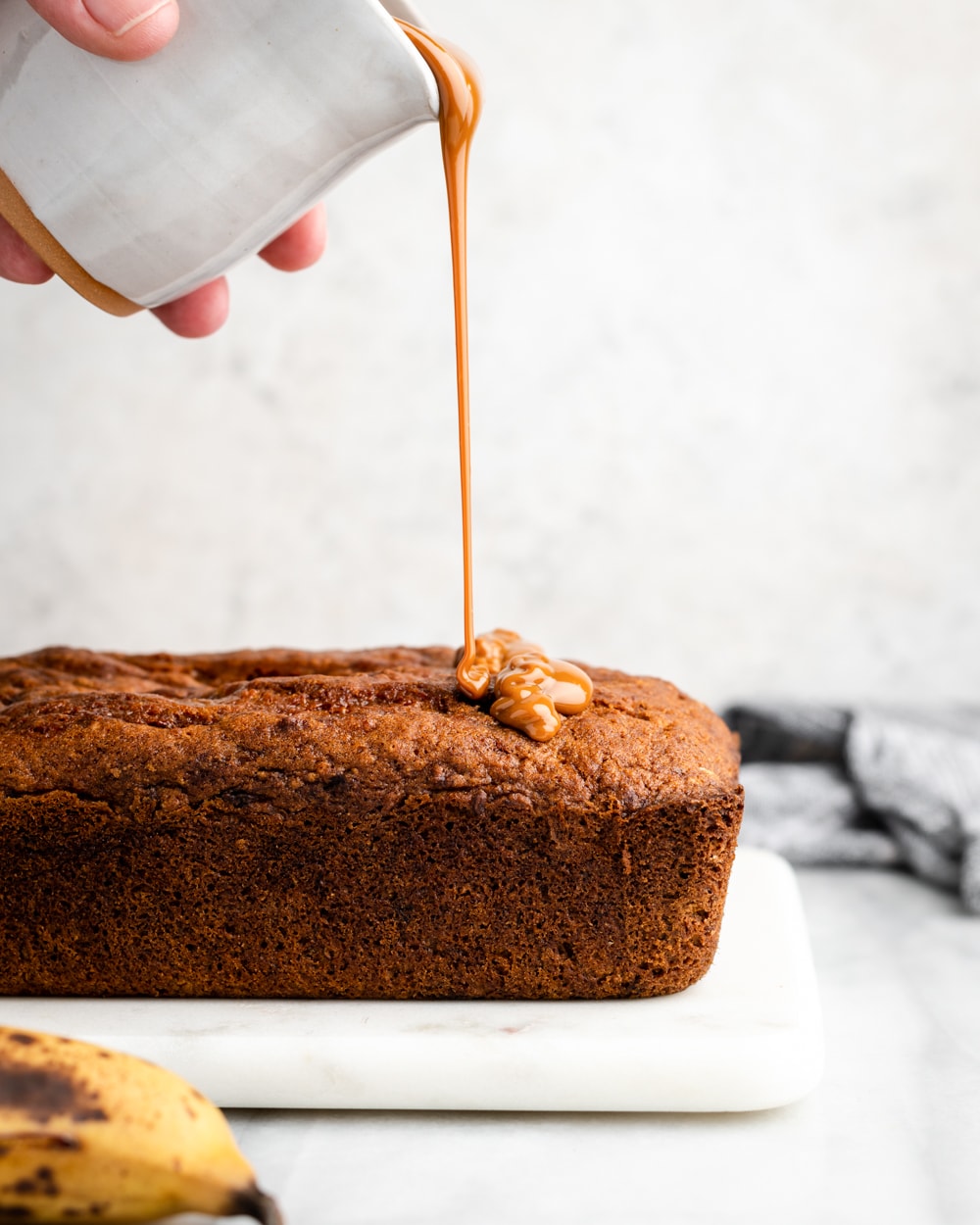 baked banana bread with dulce de leche being poured on top