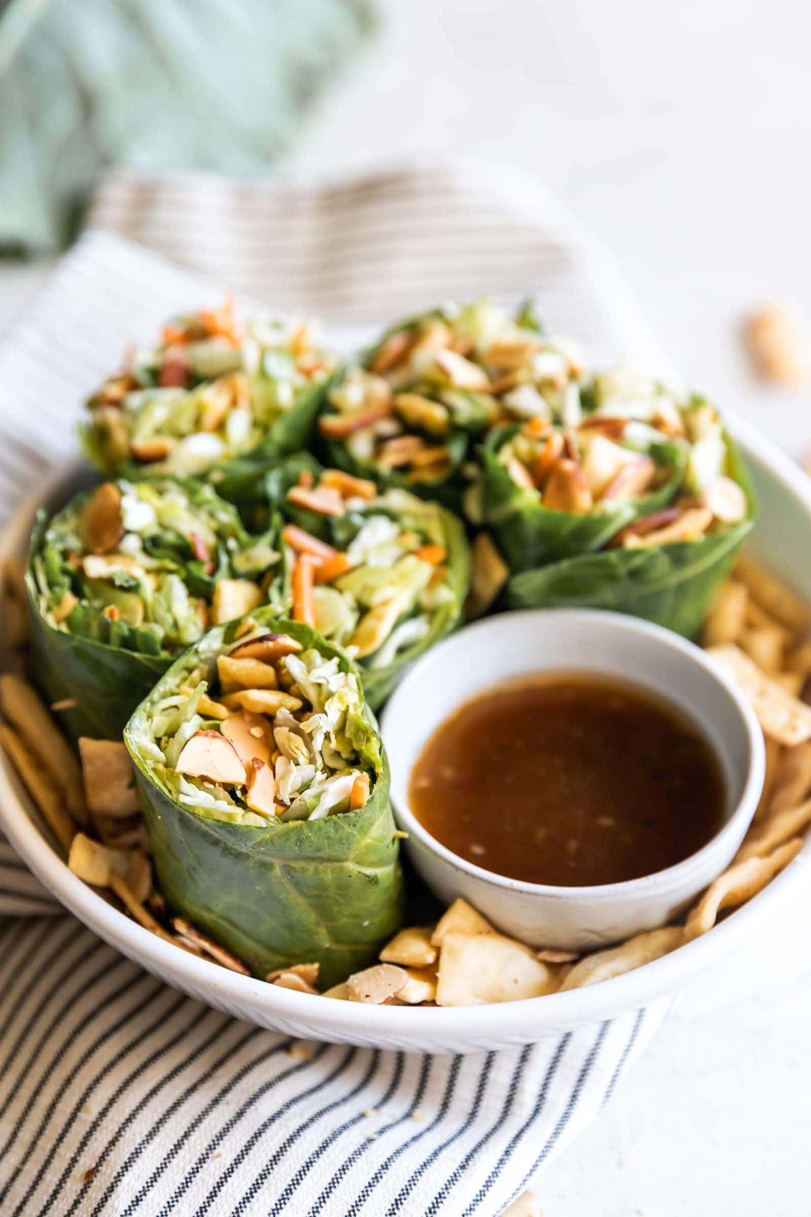 Simple collard green wraps made with avocado, savory green cabbage, carrots, celery, green onions, cilantro, toasted slivered almonds, crisp wontons, and sweet sesame ginger dressing!
