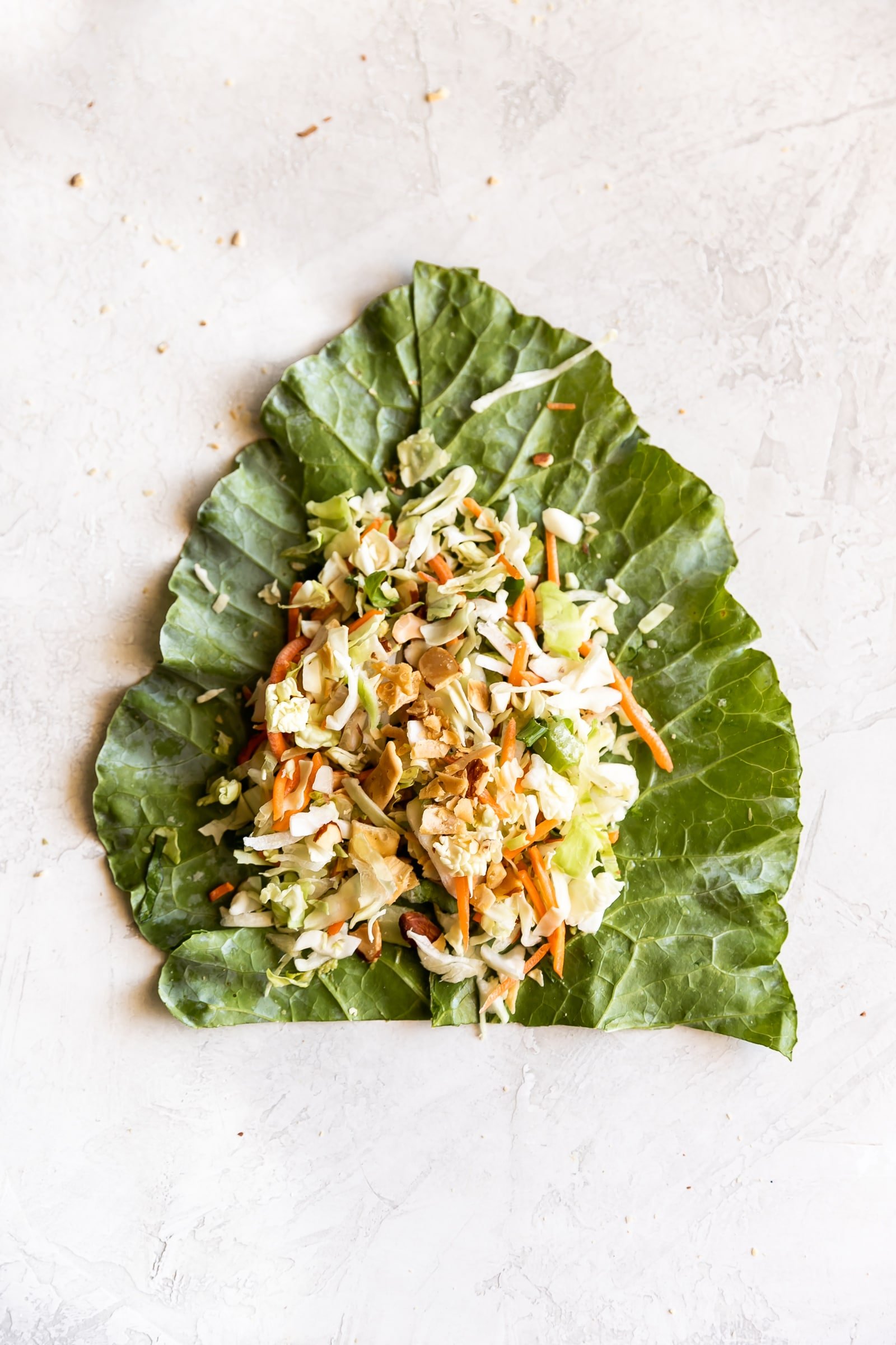 Simple collard green wraps made with avocado, savory green cabbage, carrots, celery, green onions, cilantro, toasted slivered almonds, crisp wontons, and sweet sesame ginger dressing!