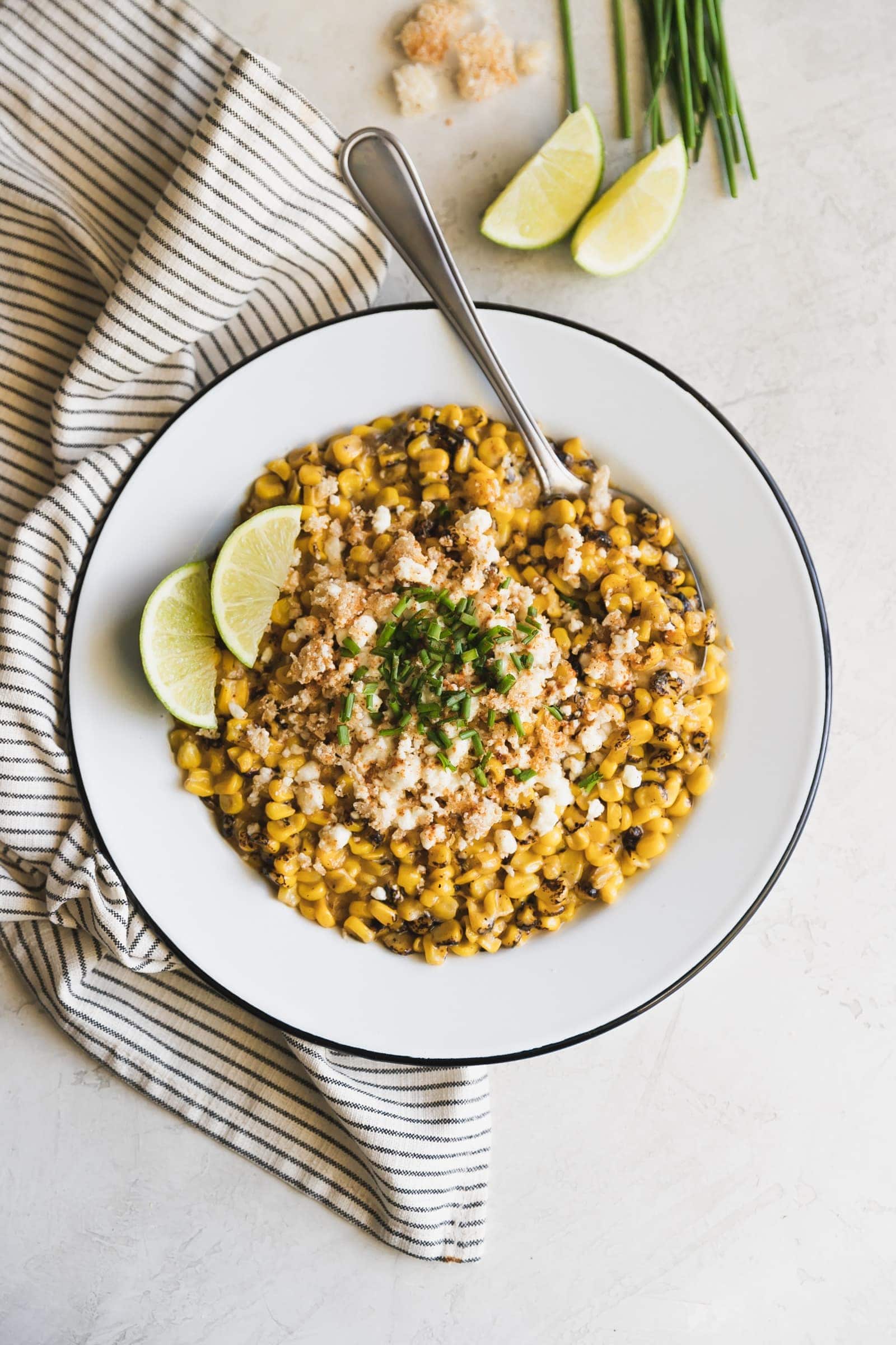 Easy Chipotle Mexican Street Corn. Fire roasted corn mixed with spicy chipotle mayo and mozzarella then topped with crushed pork rinds, crumbled cotija and chives.