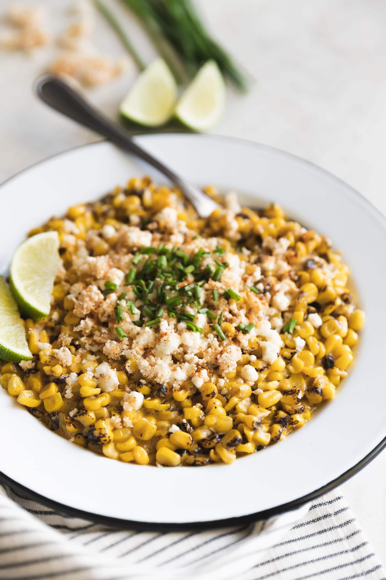 Easy Chipotle Mexican Street Corn. Fire roasted corn mixed with spicy chipotle mayo and mozzarella then topped with crushed pork rinds, crumbled cotija and chives.