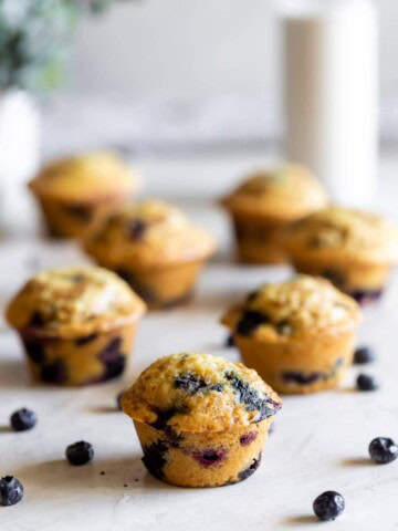 easy blueberry muffins on table with blueberries all around