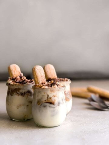 Three tiramisu cups with mascarpone mousse and espresso soaked ladyfingers