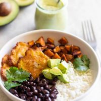 A hearty vegan Cuban bowl made with rice, sweet potatoes, black beans, tostones (plantains) and dairy-free, creamy avocado ranch dressing!
