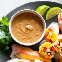 a plate with fresh spring rolls and vegan peanut sauce in a bowl