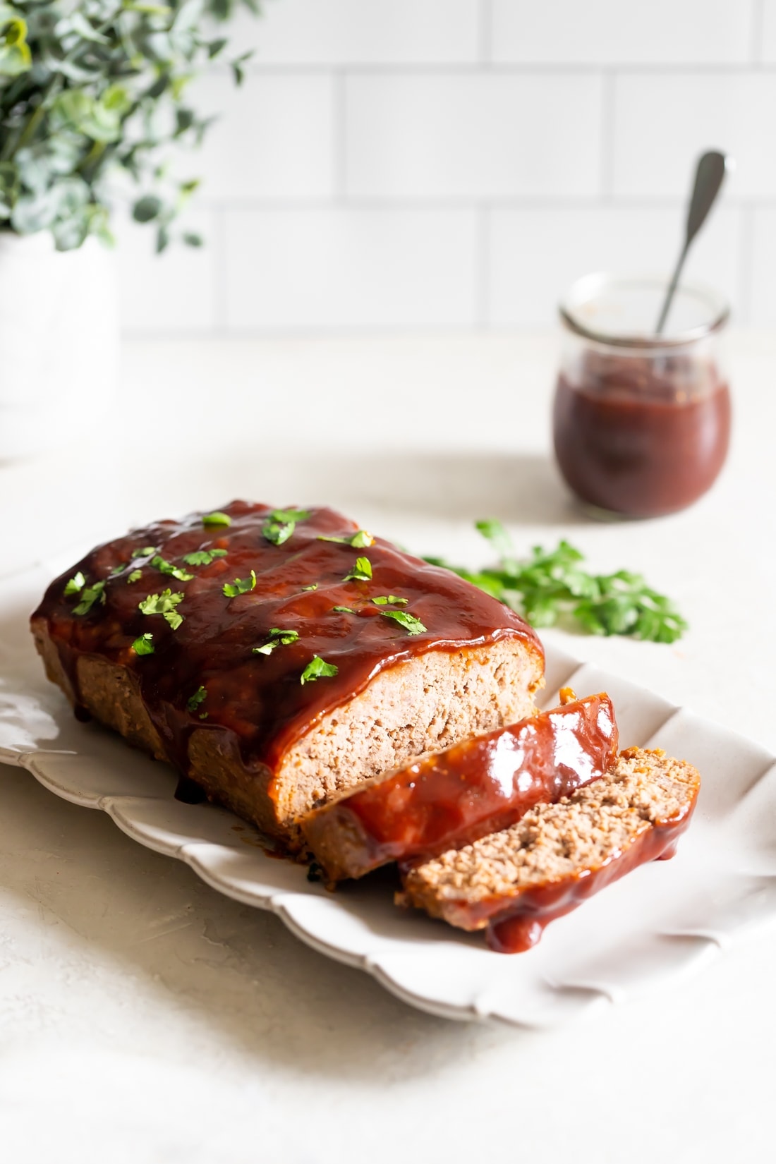 guava bbq sauce meatloaf recipe sliced on a rectangular plate with chopped cilantro 