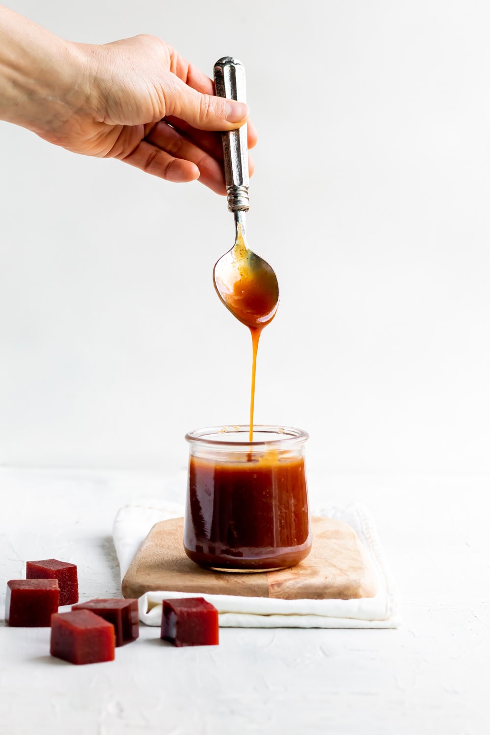 guava caramel sauce in a jar with a spoon drizzling sauce into the jar