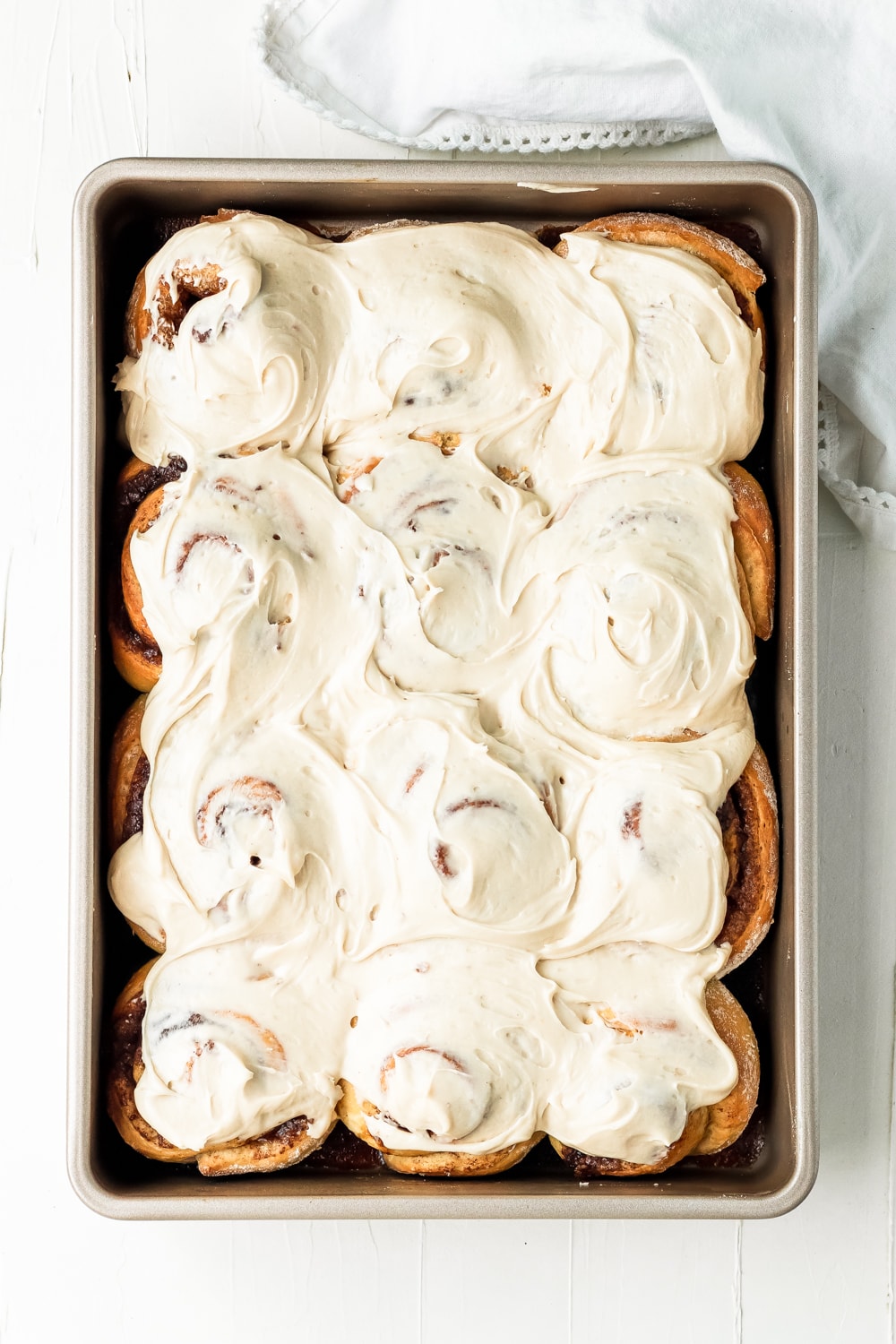 cinnamon rolls with thick icing on a baking dish