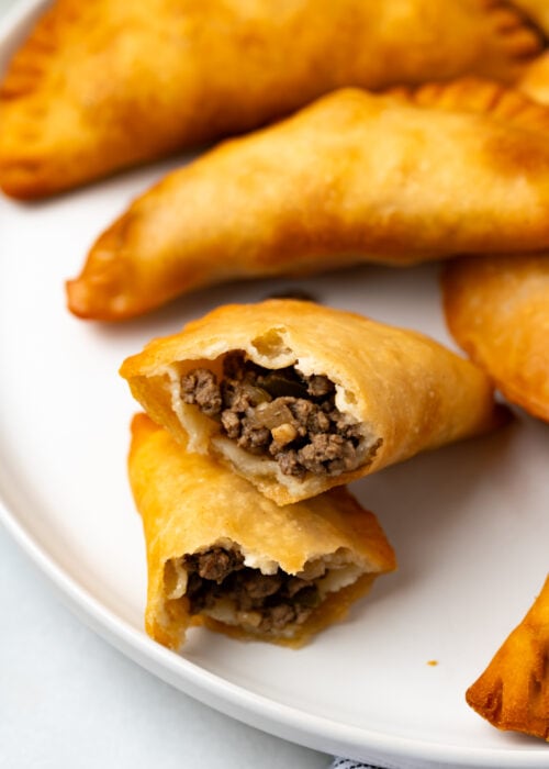 A beef filled cuban empanadas made with homemade empanada dough with more empanadas on the same plate