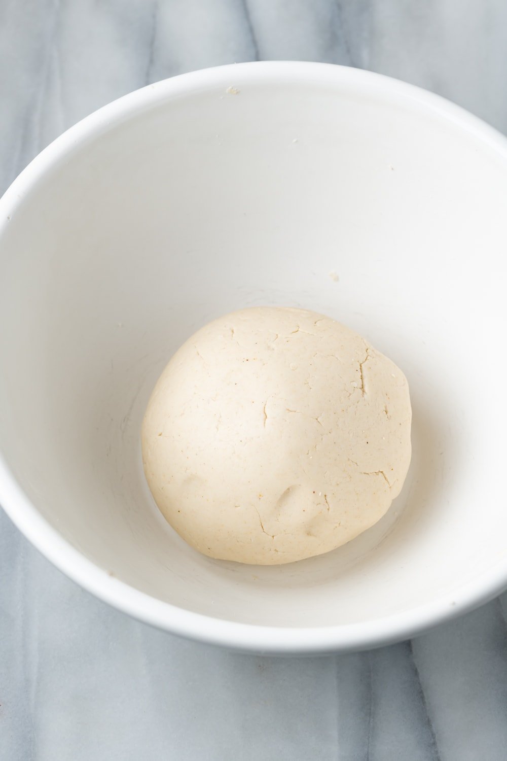 Empanada dough in a smooth ball in a white bowl 