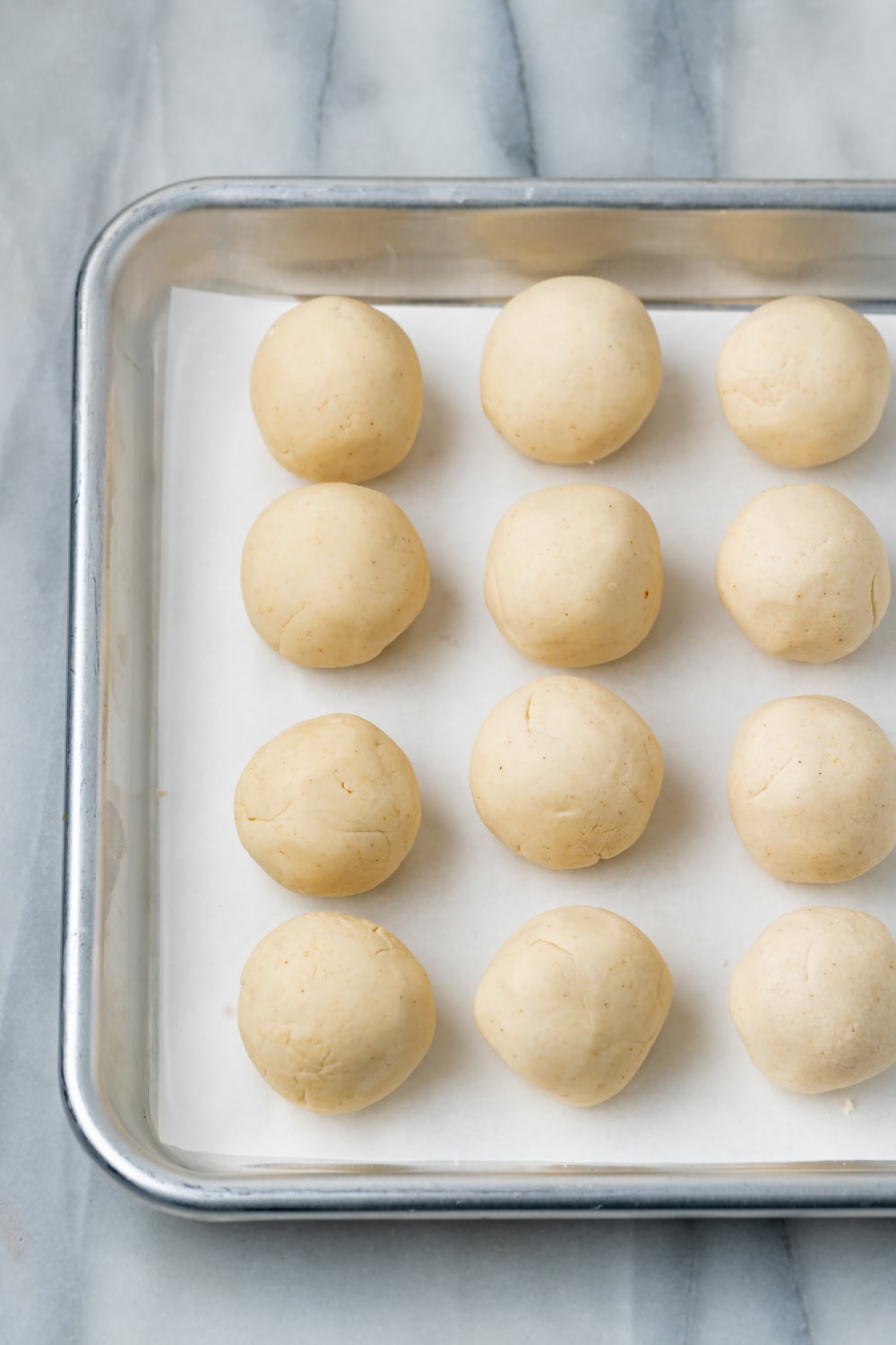 12 Empanada dough balls on a parchment lined baking sheet 