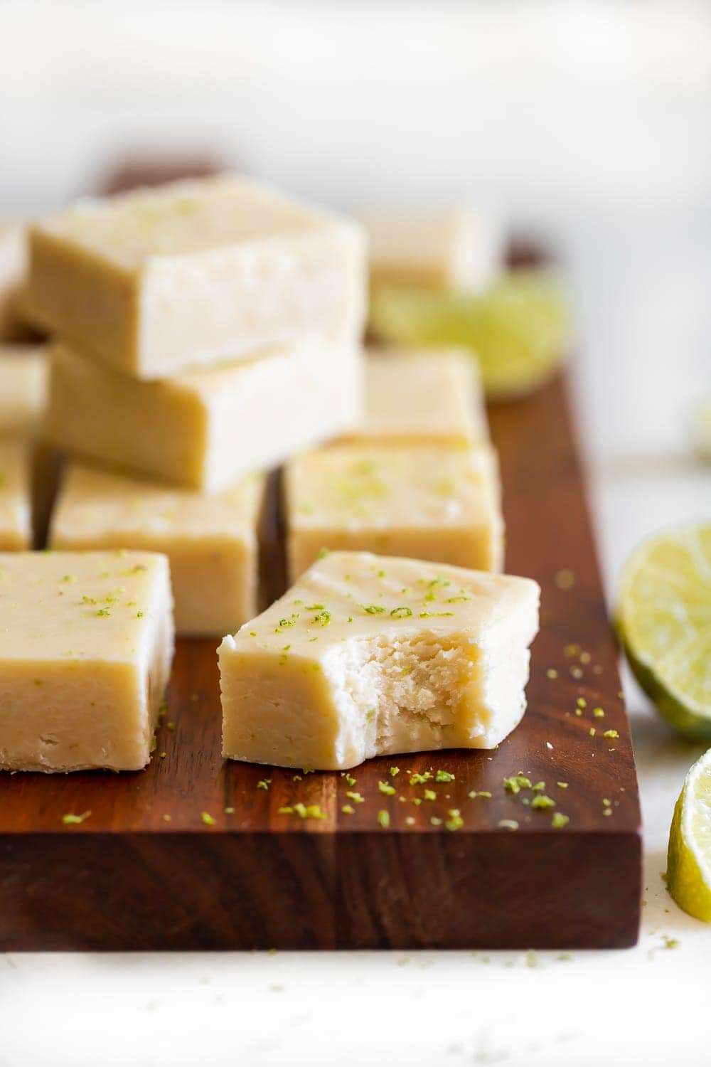 white chocolate key lime fudge with a bite mark on a wood cutting board