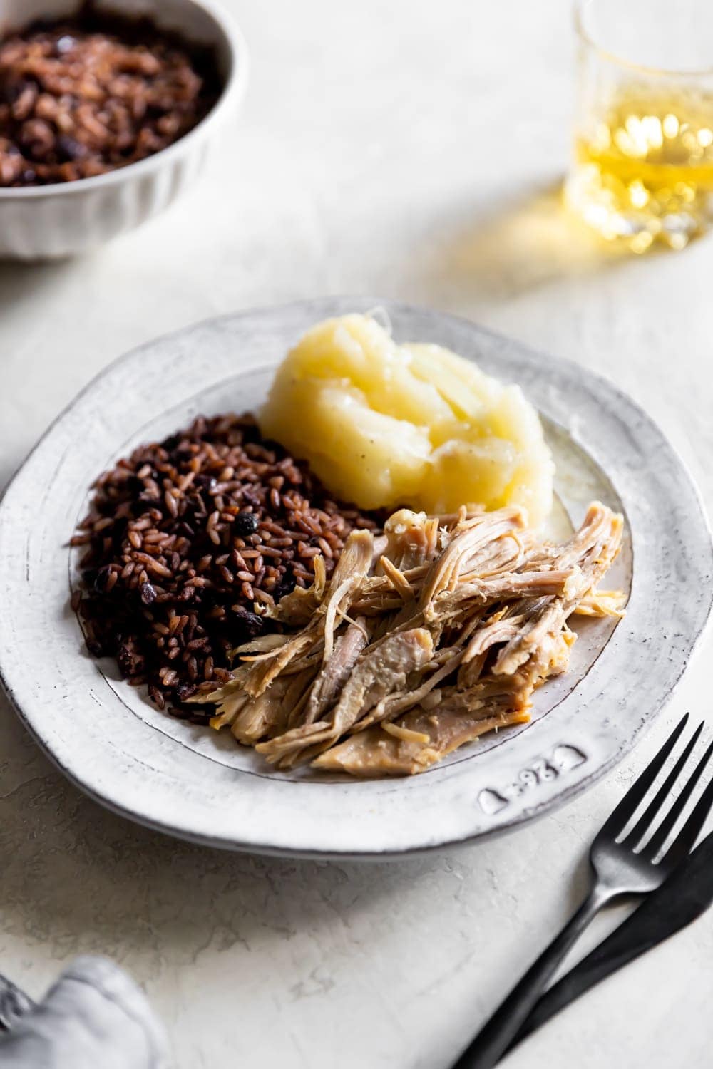 Kubanischer Schweinebraten, kubanische schwarze Bohnen, Reis, Yuca mit Mojo auf einem Teller