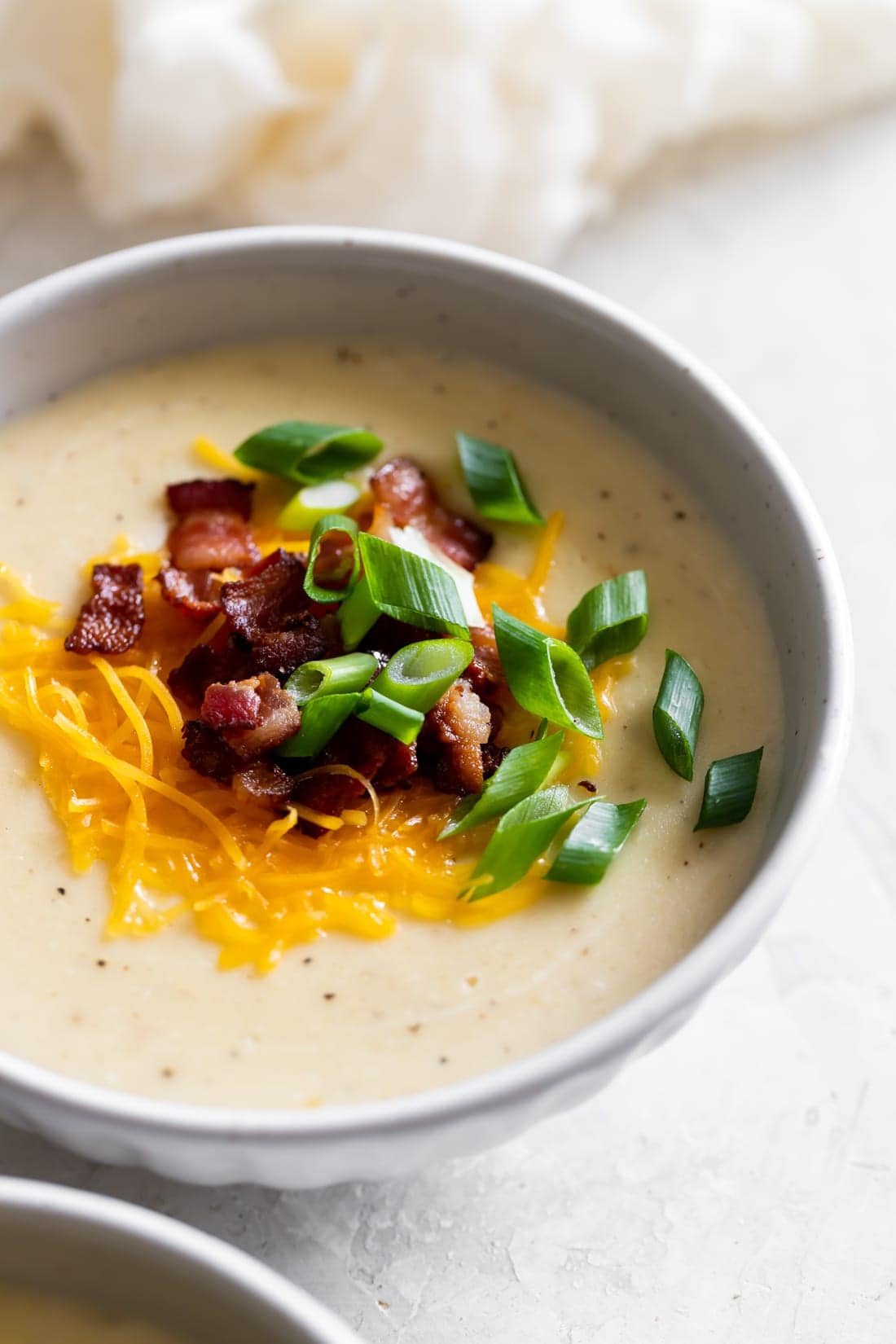 bowl of loaded baked potato soup with bacon, cheese, green onions as toppings