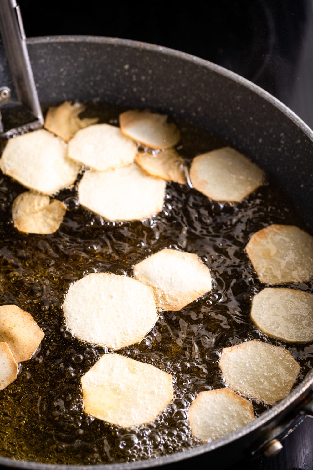 slices of malanga being fried in oil in a Dutch oven