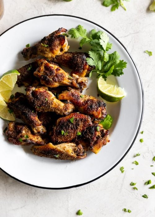 citrus and garlic marinated chicken wings on a plate with lime and cilantro