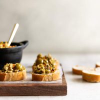 A simple yet irresistible appetizer made with tart, briny olives, capers, fresh garlic, pepper, and olive oil then served on toasted baguette slices brushed with olive oil.