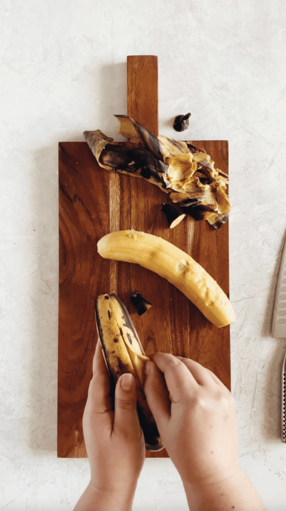 peeling ripe plantains on a wooden block