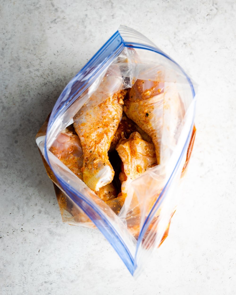 chicken pieces for pollo asado in a plastic freezer bag with mojo marinade and spices