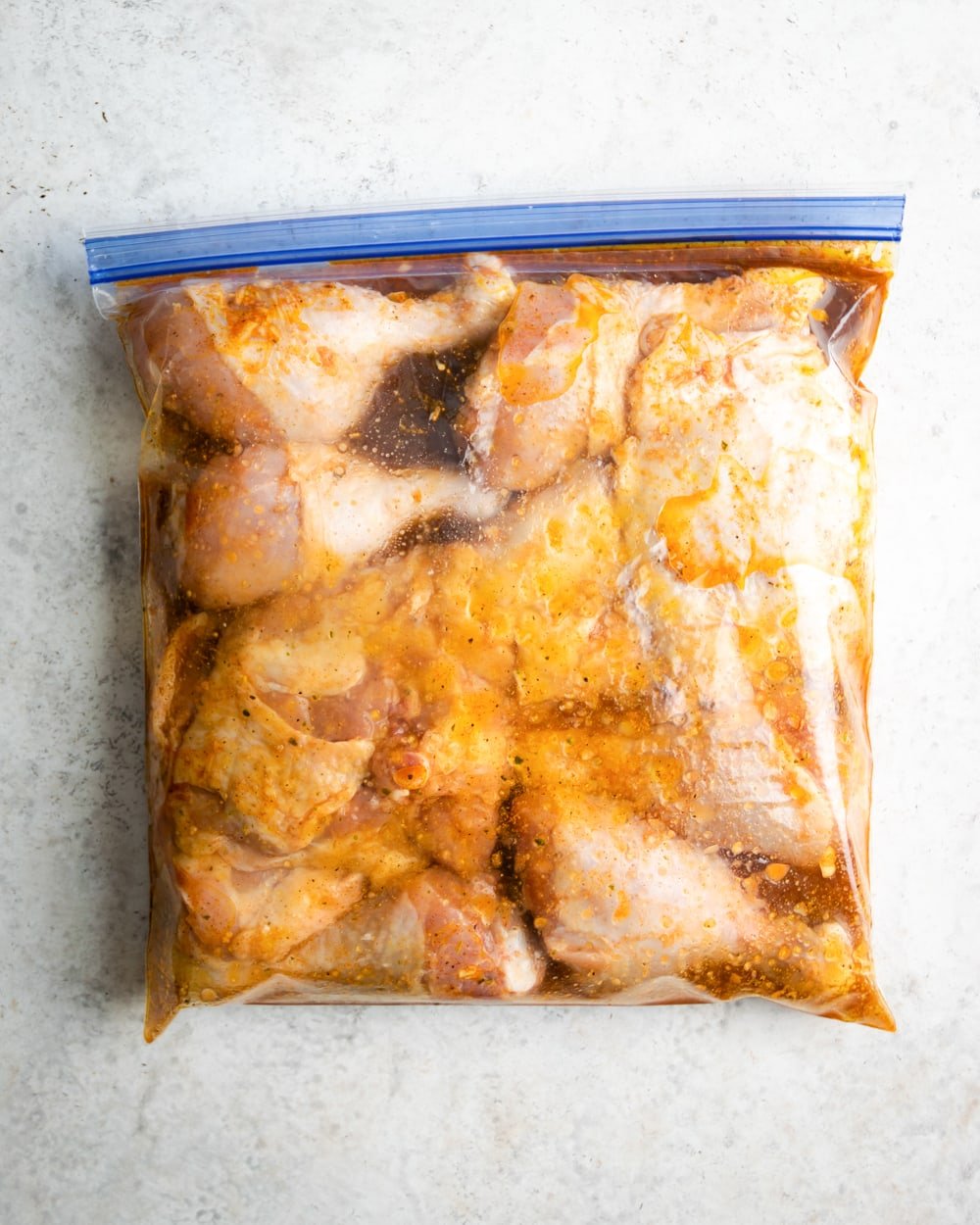 chicken thighs and chicken drumbsticks marinating in mojo marinade in a zip lock bag