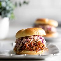 pulled pork sandwich with slaw on a white plate
