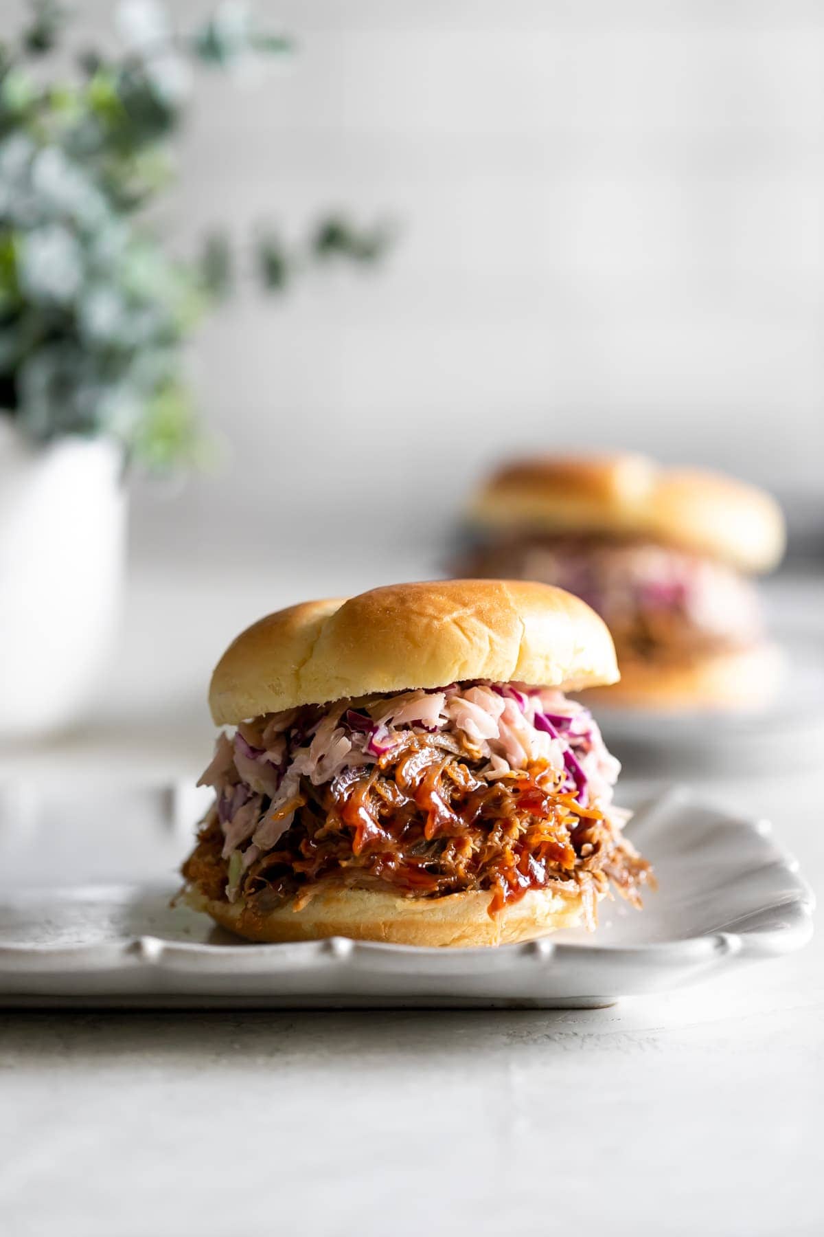 pulled pork sandwich with slaw on a white plate