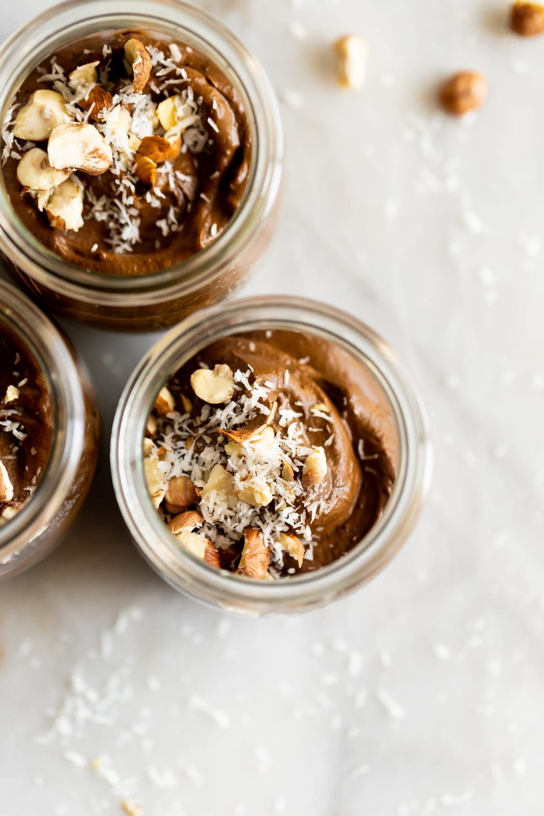 A creamy dairy-free avocado chocolate mousse made with just 5 ingredients then topped with coconut flakes and chopped hazelnuts!