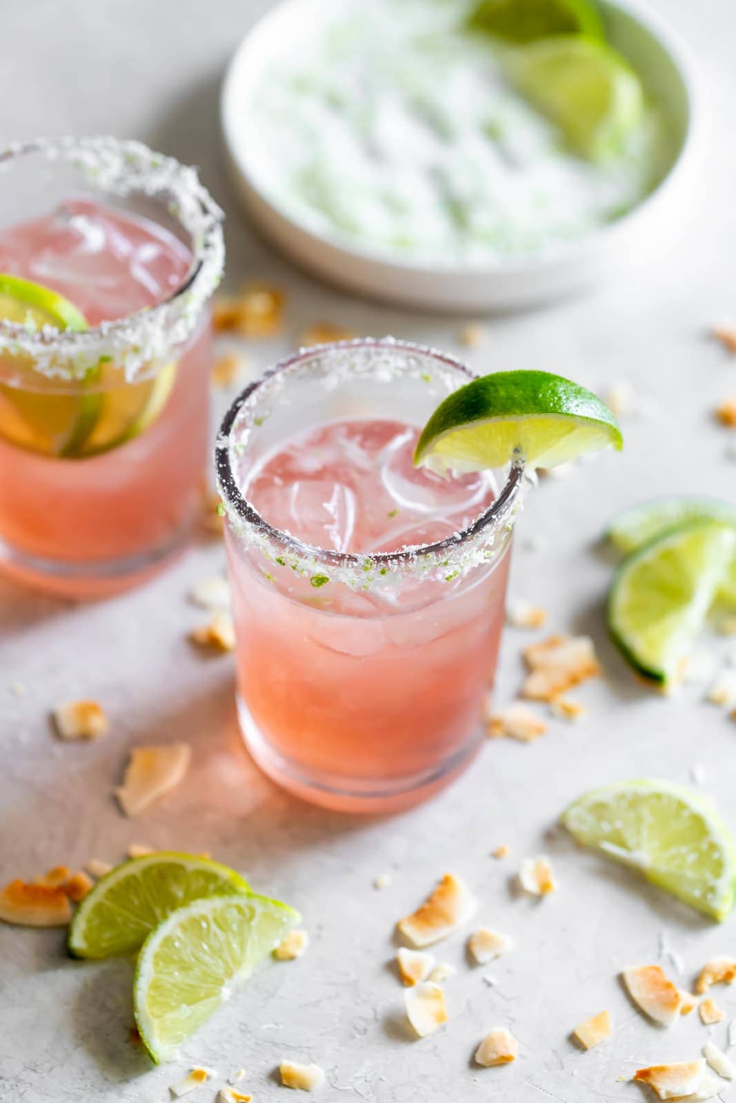 guava margarita in a glass with a coconut lime salted glass rim and a lime wedge