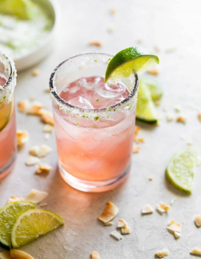 guava margarita on the rocks with a coconut lime salted glass rim and a lime wedge