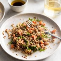 Salmon served with quinoa, tomatoes, onions, and arugula