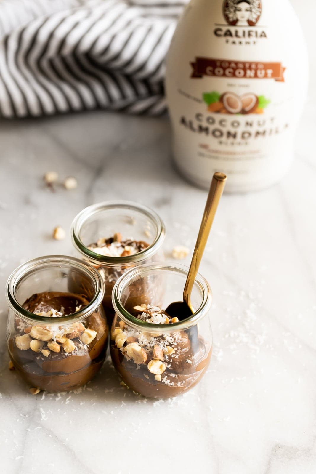 A creamy dairy-free avocado chocolate mousse made with just 5 ingredients then topped with coconut flakes and chopped hazelnuts!