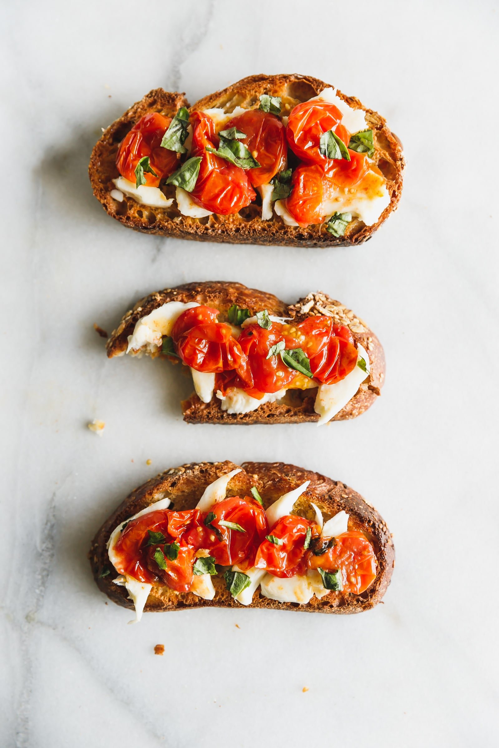 Caprese salad on toast! Cherry tomatoes are roasted until bursting and lightly browned then served with fresh mozzarella on thick, olive-oil-toasted bread.