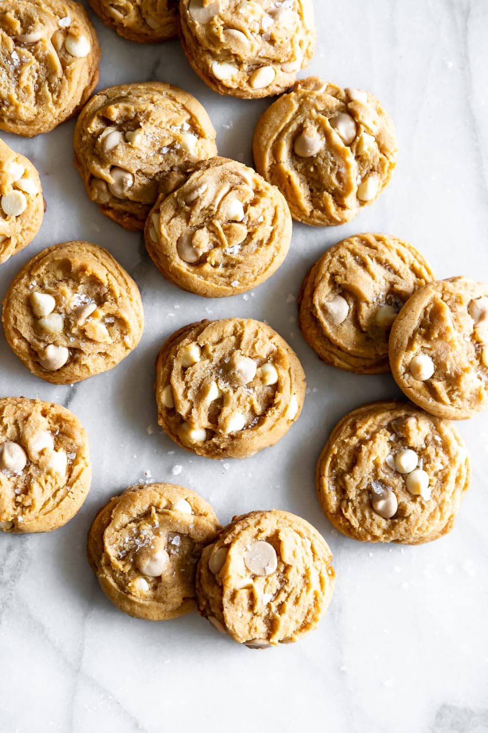 White chocolate chip cookies with flaky salt on a marble slab