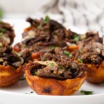 Stuffed plantain cups on a white plate stuffed with vaca frita (crispy beef).