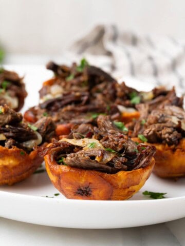 Stuffed plantain cups on a white plate stuffed with vaca frita (crispy beef).