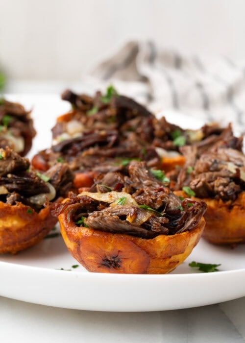 Stuffed plantain cups on a white plate stuffed with vaca frita (crispy beef).