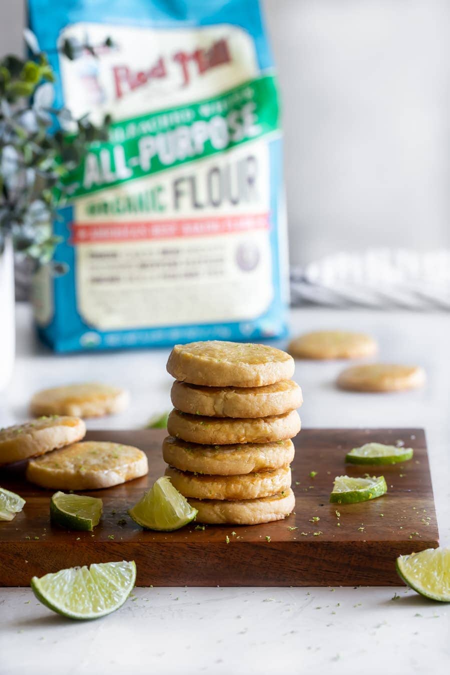 uma pilha dos melhores bolinhos de cookies em uma placa de corte de madeira com fatias de limão